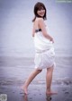 A woman in a white dress walking on the beach.