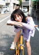 A young woman leaning on a yellow bike on the street.