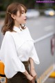 A woman wearing a white blouse and a brown skirt.