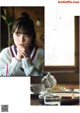 A woman sitting at a table with a cup of coffee.