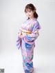 A woman in a purple and blue kimono posing for a picture.