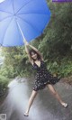 A woman in a black dress holding a blue umbrella.