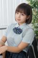 A woman in a school uniform sitting on a chair.