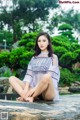 A woman sitting on a rock in a park.