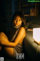 A woman sitting on a couch next to a lamp.