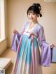 A woman in a purple and blue hanbok is posing for a picture.