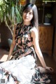 A woman in a floral dress sitting on the floor.