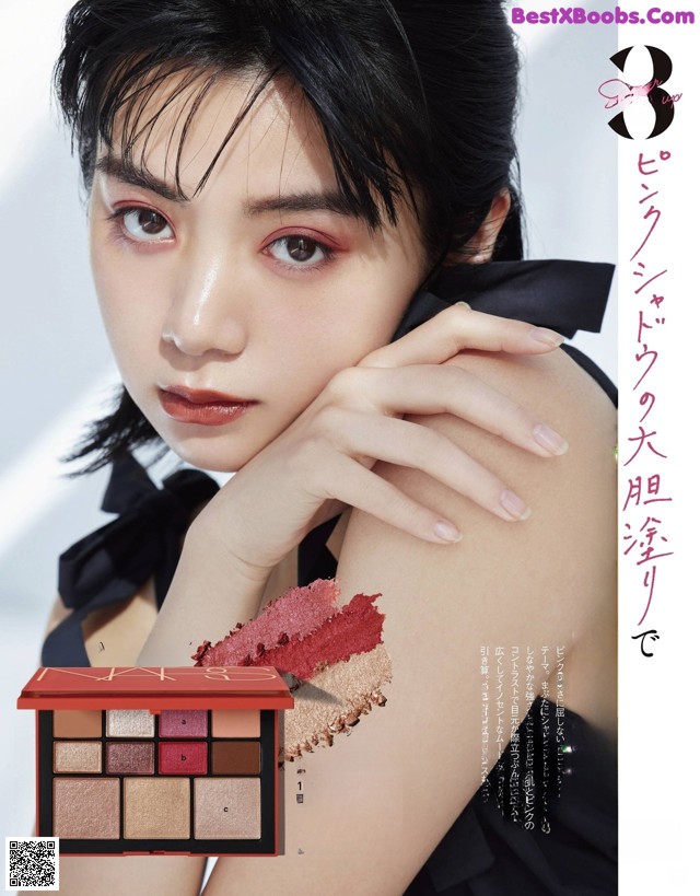 A woman in a black dress holding a makeup palette.