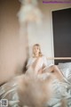 A woman sitting on top of a bed in a white dress.