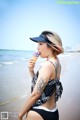 A woman in a bathing suit eating an ice cream cone on the beach.