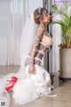 A woman with tattoos sitting on the floor in a wedding dress.